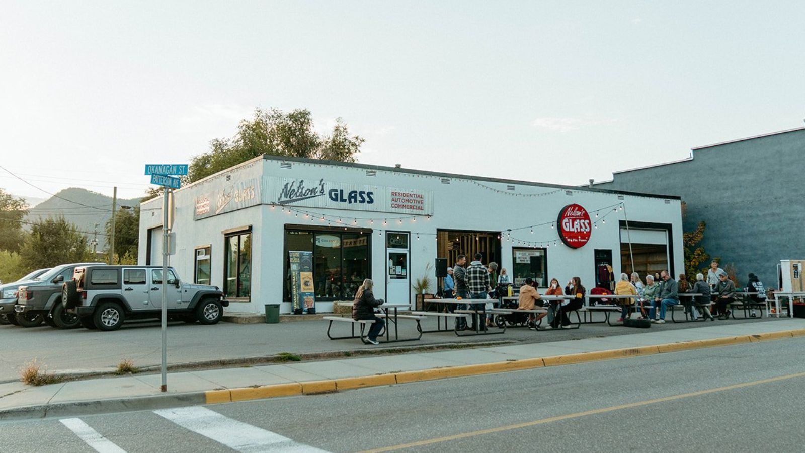 Neighbours gather at picnic tables outside the Nelson's Glass storefront on Okanagan Street in Armstrong, BC